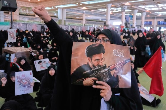 Une femme en deuil scande des slogans tout en tenant une affiche représentant graphiquement le guide suprême iranien, l’ayatollah Mojtaba Khamenei, lors d’une cérémonie commémorant le défunt guide suprême, l’ayatollah Ali Khamenei, à la grande mosquée Imam Khomeini Mosalla à Téhéran, mardi 14 juillet 2026.