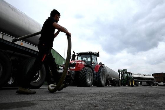 Un agriculteur tenant un tuyau d'arrosage en attendant de remplir des citernes pour aider les pompiers à lutter contre l'incendie de forêt à Saint-Jean-d'Illac, à l'ouest de Bordeaux, le 27 juillet 2026.