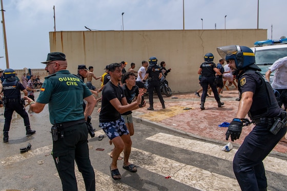 Des officiers de police espagnols face à des migrants à Ceuta, le 30 juillet 2026.
